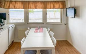 Il comprend une cuisine avec une table et des chaises blanches ainsi que 2 fenêtres. dans l'établissement Gorgeous Home In Grythyttan With House Sea View, à Grythyttan