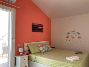 um quarto com 2 camas e uma parede laranja em Flamingo's House in Sant'Antioco, Sardinia em SantʼAntìoco