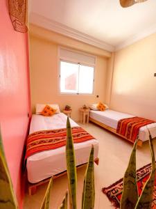 duas camas num quarto com plantas e uma janela em Monkey's Guest House - Appartement roof top terrasse privée vue sur mer em Tamraght Ouzdar