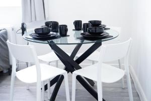 a glass table with four white chairs around it at Brighton City Centre Apartment with Two Parking Spaces in Brighton & Hove