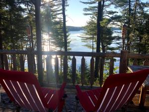 two chairs on a deck with a view of a lake at Beddington Lake Log Cabin 