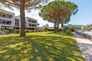 un parque con árboles frente a un edificio en Luxury Garden apartment with stunning Cannes Marina views, en Mandelieu-la-Napoule