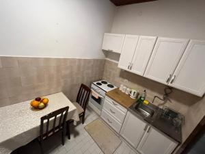 a kitchen with white cabinets and a table with a bowl of fruit at Korra in Herceg-Novi