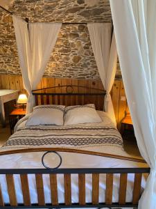 1 dormitorio con cama con dosel y pared de piedra en Maison d'Hôtes Hameau de Taur, en Villefranche-dʼAlbigeois