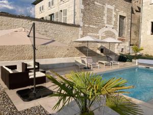 a pool with chairs and umbrellas next to a building at Le Clos des Riceys - La Villa Lombardi in Les Riceys