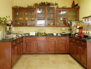 a kitchen with wooden cabinets and a refrigerator at Days Inn & Suites by Wyndham Swainsboro in Swainsboro