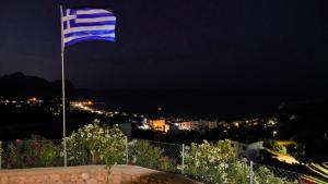 una bandera azul y blanca ondeando sobre una ciudad por la noche en Villa Leonardo, en Archangelos