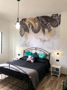 een slaapkamer met een zwart bed en een muurschildering bij Il melograno in Usini