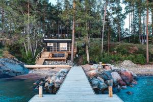 a house with a wooden walkway leading to the water at Saunamäki Resort - State of the Art Coastal Villa in Salo