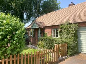 una pequeña casa con una valla de madera y un patio en Divine, detached countryside cottage near Ludlow., en Ludlow