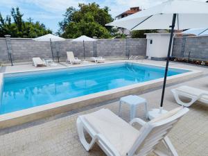 a swimming pool with two chairs and an umbrella at Аpartment Bella Vista in Obzor