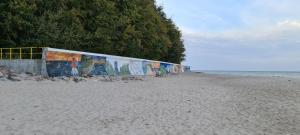 Una pared en una playa con graffiti. en Marina Apartamenty, en Rozewie