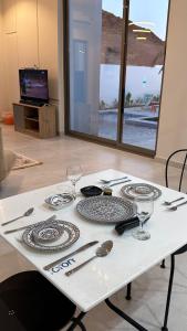 a white table with plates and wine glasses on it at شاليهات بلاسيو 