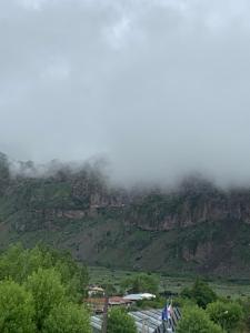een berg gehuld in wolken met een stad erop bij Guest House Oxygen in Kazbegi