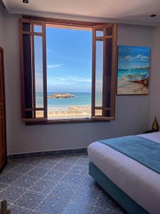 a bedroom with a window with a view of the beach at Riad Mellah in Essaouira