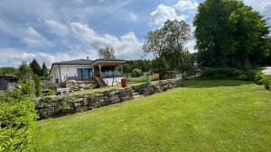 uma casa com uma parede de pedra e um quintal em Lipno Villa Beach - Lipno Stausee - Lakeside em Loučovice