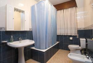 La salle de bains est pourvue d'un lavabo, de toilettes et d'un rideau de douche bleu. dans l'établissement Pitis, à Bueu