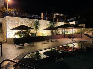 a patio with umbrellas and chairs and a pool at night at Villa Rodanthi Sivota in Syvota