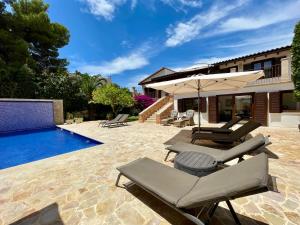 a patio with chairs and an umbrella next to a swimming pool at Villa Buena Vista in Palmanova