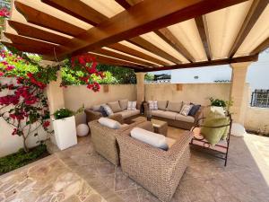 a patio with wicker chairs and couches under a wooden roof at Villa Buena Vista in Palmanova