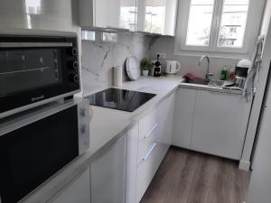 a white kitchen with a sink and a microwave at Magnifique Studio de 25 m2 in Paris