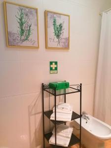 La salle de bains est pourvue d'un lavabo et d'une étagère avec des serviettes. dans l'établissement Cocoon Guest House Vendas Novas, à Vendas Novas