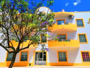 un bâtiment orange et blanc avec un arbre dans l'établissement Cocoon Guest House Vendas Novas, à Vendas Novas