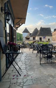 a patio with tables and chairs on a building at Hôtellerie de l'Abbaye Saint Amand in Saint-Amand-de-Coly