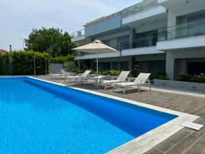 a blue swimming pool in front of a building at Dina's Holiday Apartment with Pool in Nikiti in Nikiti