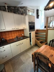cocina con armarios blancos y mesa de madera en GITE DES ANGES, en Barret-sur-Meouge