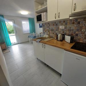 cocina con armarios blancos y encimera de madera en Apartmány nad Tajovom en Banská Bystrica