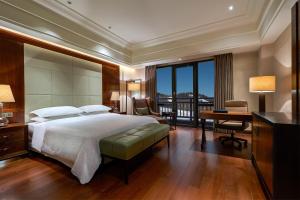 a bedroom with a large bed and a desk and a desk at Sheraton Changbaishan Resort in Fusong