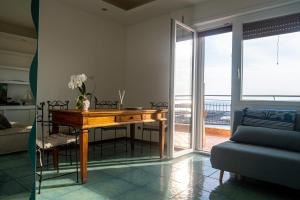 uma sala de estar com uma mesa de madeira e uma varanda em MARE FUORI APARTMENT em Civitavecchia