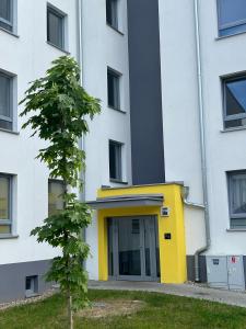 a building with a yellow door next to a tree at Apartament Elle in Malbork