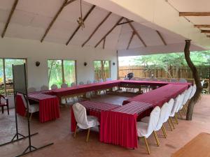 una gran sala de conferencias con mesas rojas y sillas blancas. en Hillstone Safari Lodge en Kimana