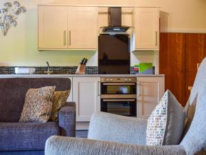 a living room with two chairs and a kitchen at The Studio At Malt Kiln Cottage in Grizebeck