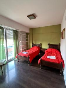 a bedroom with two beds with red sheets in it at Departamento Centro in Olavarría