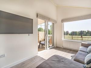 a living room with a couch and a flat screen tv at The Tranquil Orchard - Nuthatch-uk32791 in Mouswald