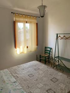 a bedroom with a bed and a chair and a window at La Mandola in Castiglione dʼOrcia