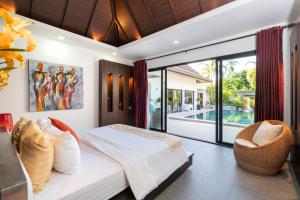 a bedroom with a bed and a view of a pool at The Thara Villa Surin Beach in Ban Lum Fuang +87 photos