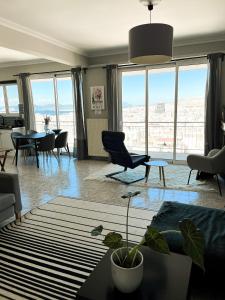 a living room with a table and chairs and windows at Porto Pireo Penthouse Sea View in Piraeus