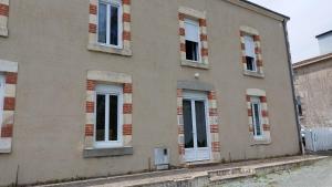 a building with white doors and windows on a street at AU PIED DU MOULIN in Saint-Hilaire-de-Voust