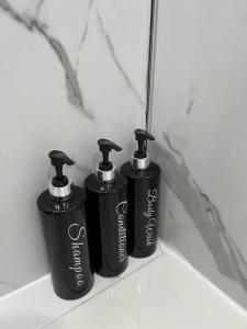 three black bottles sitting on a shelf in a bathroom at Erskine Apartment in Erskine