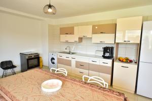 a kitchen with white cabinets and a table and chairs at Casa Ryn in Vama Veche