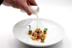 una persona está vertiendo salsa en un plato de comida en Zur Weinsteige, en Stuttgart