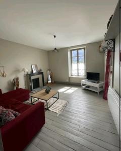 ein Wohnzimmer mit einem roten Sofa und einem Kamin in der Unterkunft Appartement Le feron in Vic-sur-Cère