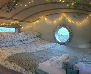 1 dormitorio con 1 cama con toallas y ventana en Secluded Shepherds Hut, with a view and hot tub en Ashburton