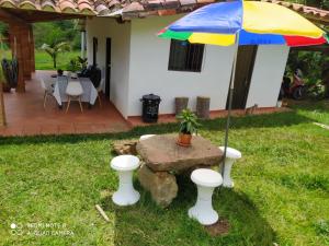 a table with a colorful umbrella in a yard at Cabaña villa lola in San Gil