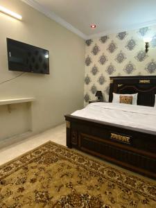 a bedroom with a bed and a flat screen tv at Dream Inn Guest House in Islamabad