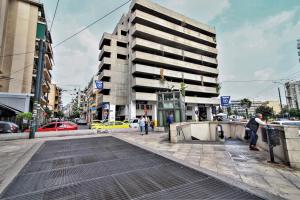 um edifício alto numa rua da cidade com carros em Dimosthenis_Loft1 em Atenas